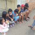 Para relawan bergerak sambil membagikan susu gratis kepada anak-anak dan warga.